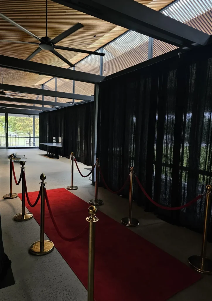 Indoor venue featuring black backdrop curtain with red carpet path