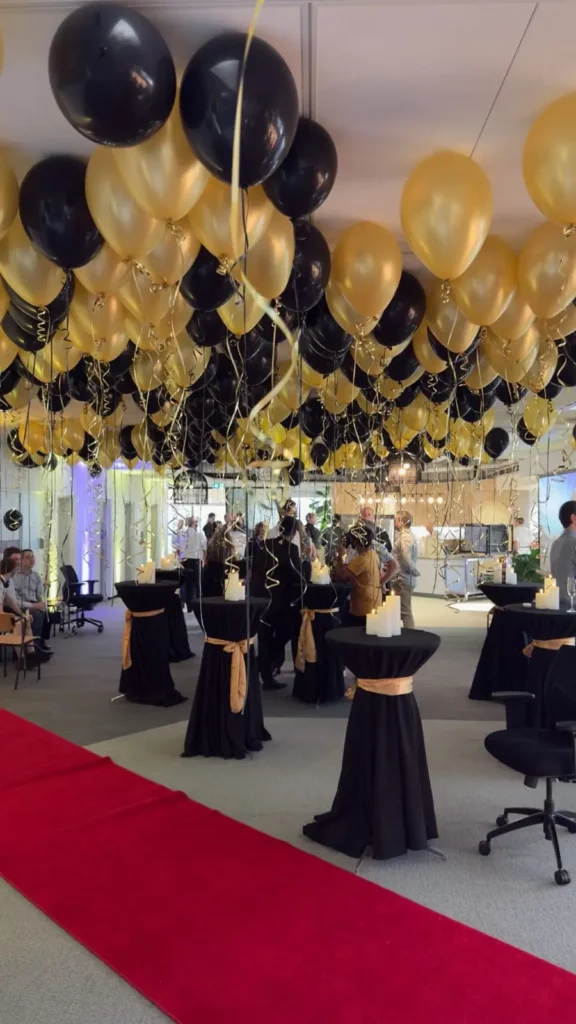 Event hall filled with black and gold decorative ceiling balloons