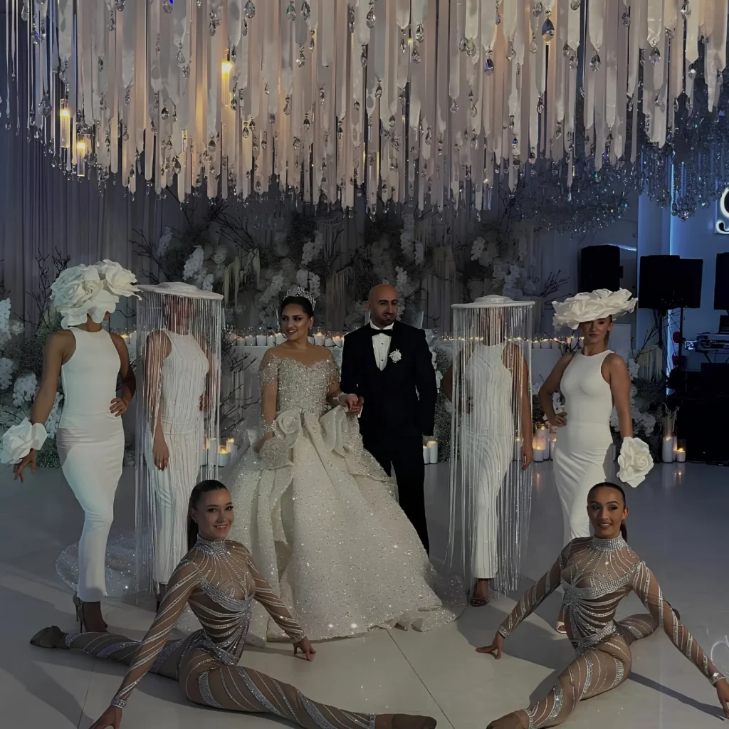 Bride and groom with dancers in white fringed tassel hats.