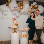 Couple Standing Beside Their Engagement Cake with Balloon and Floral Decor