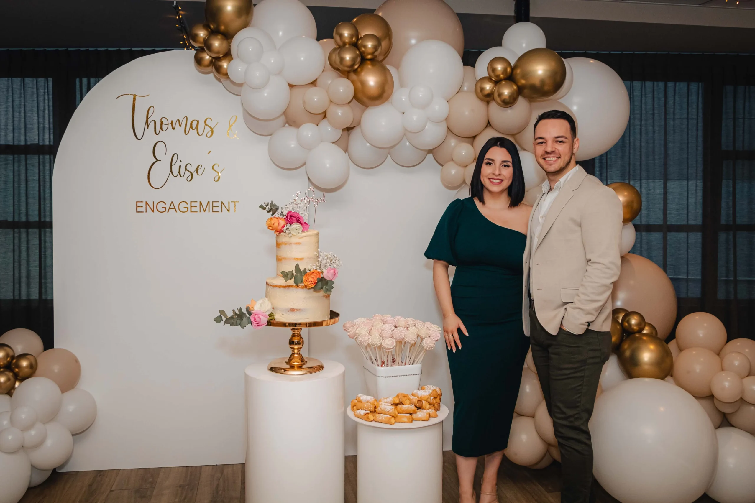 Couple Standing Beside Their Engagement Cake with Balloon and Floral Decor