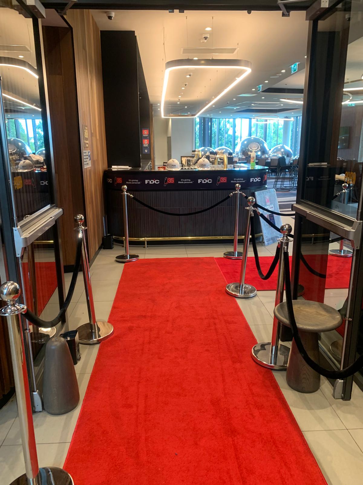 Red carpet runner leading through glass entrance of event building