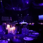 Purple glowing candles decorating tables in dark event space
