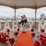 Couple embracing under a gazebo with harbor views.