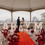 Couple inside a pavilion with "MARRY ME" letters.
