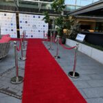 Red carpet entrance path with silver stanchions inside venue