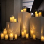 Lit pillar candles displayed on white pedestals at night