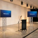 Corporate presentation stage featuring dual digital display monitors setup