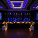 Dimly lit event hall with blue illuminated stage backdrop setup.