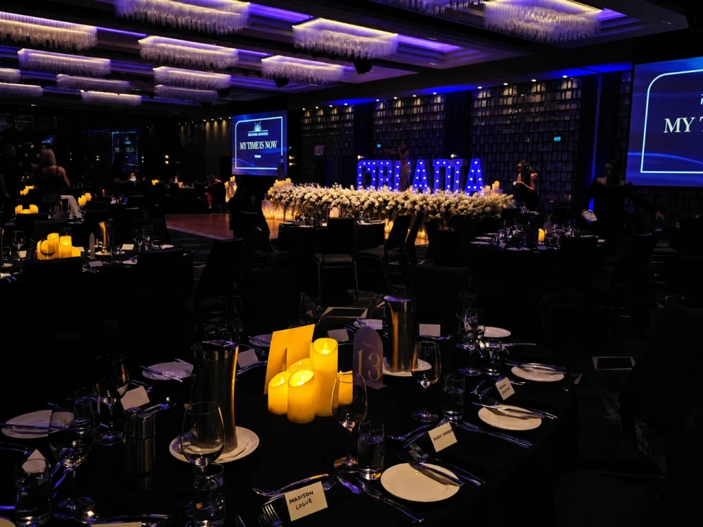 Darkened event reception space with illuminated stage display backdrop