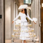 Woman in white dress and hat with champagne glass skirt