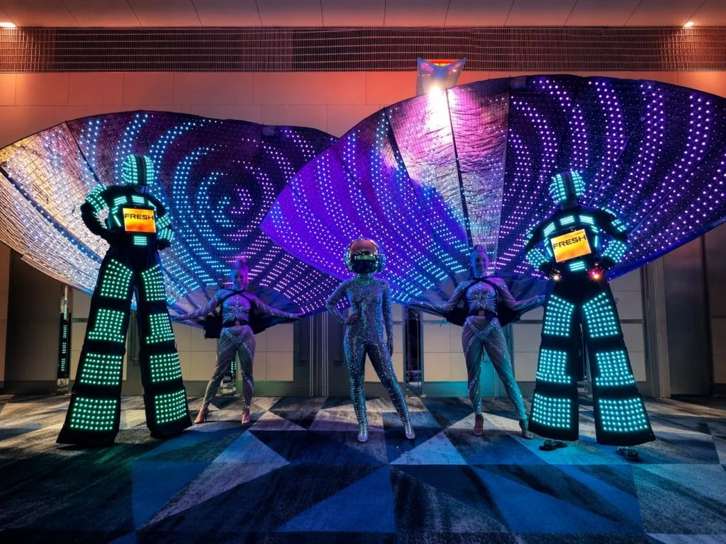 LED stilt walkers and dancers posing with illuminated fan wings