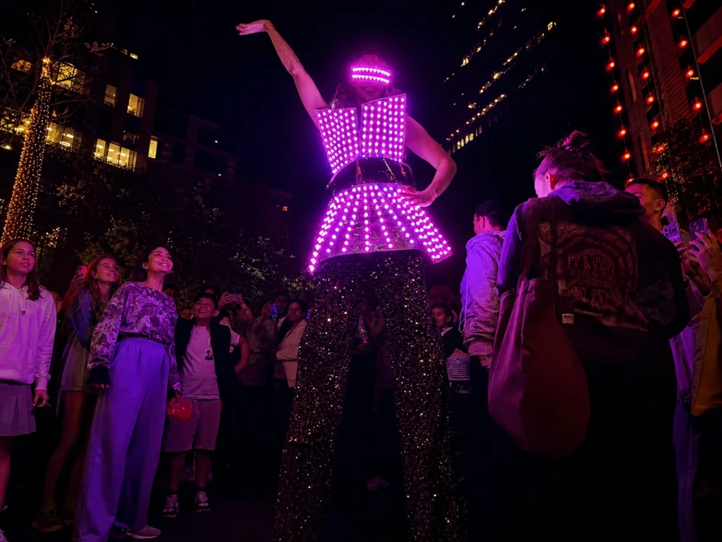 Stilt walker in illuminated LED costume performing at night