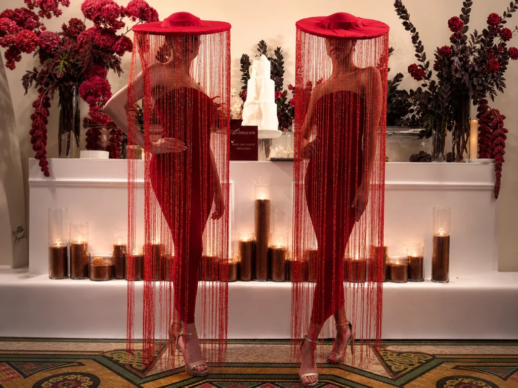 Models wearing matching red dresses and red fringed tassel hats.