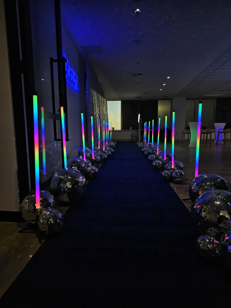 Blue carpet aisle flanked by vertical glowing LED light tubes