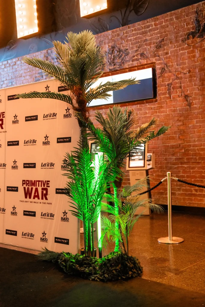 Branded media wall backdrop set up beside artificial palm tree