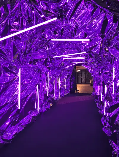 Enclosed walkway tunnel lit with dramatic purple overhead LED strips