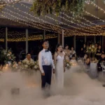 Couple dancing on a fog-covered dance floor beneath string lights