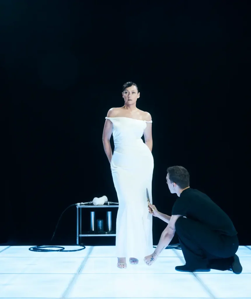 Model in white dress posing during indoor photoshoot setup