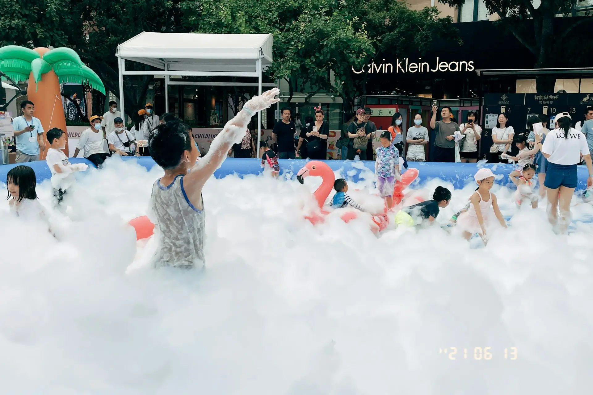Children playing inside an inflatable pool filled with thick white foam.