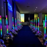 Pathway lined with glowing vertical LED light tubes at event