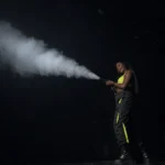 Performer shooting thick smoke effect across dark stage venue