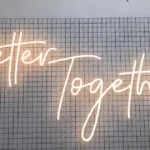 Warm glowing "Better Together" neon sign on grid backdrop