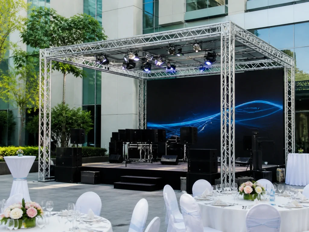 Truss frame structure set up with stage lighting and backdrop screen.