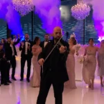 Wedding guests dancing in ballroom with purple ambient lights