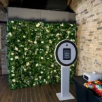 Green hedge wall backdrop set up near indoor photo booth