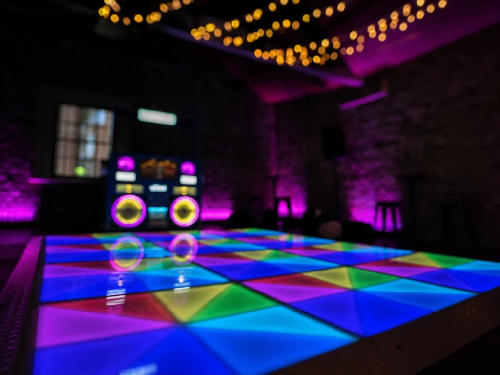 DJ setup beside illuminated dance floor in purple venue room