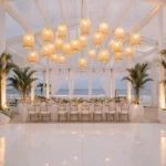 Beachfront wedding setup decorated with glowing wicker pendant lights