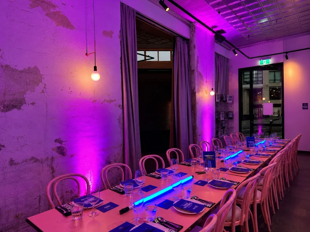 Indoor reception dining venue with intense magenta ambient uplighting setup