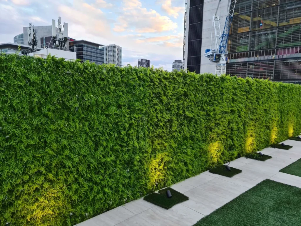 Long artificial boxwood green hedge wall installed in indoor venue.