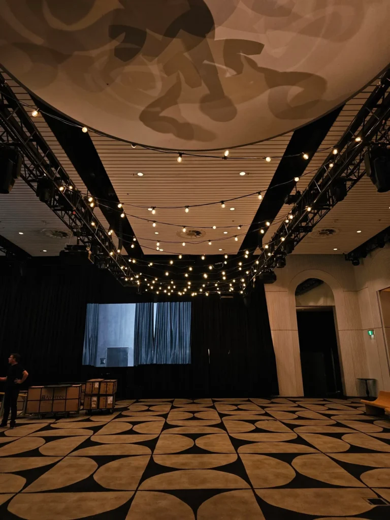 Overhead canopy of warm string lights in high ceiling venue