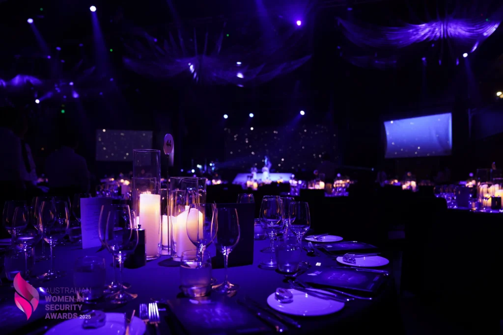 Dark event hall venue set up with purple ambient lighting.