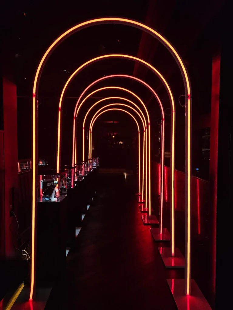 Orange neon arched light tunnel in dark event space