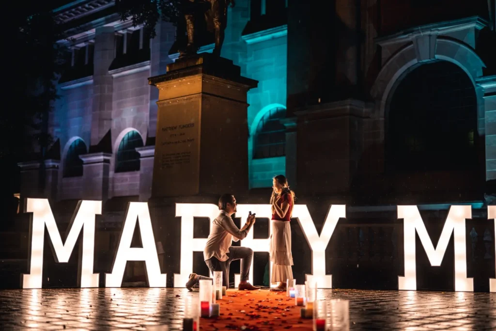 Glowing white MARRY ME marquee letters for proposal setup