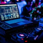 Illuminated DJ setup with laptop and mixer equipment at night.