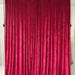 Rich red velvet drape curtain backdrop hanging on support frame
