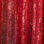 Close-up texture view of sparkling red sequin fabric drape.