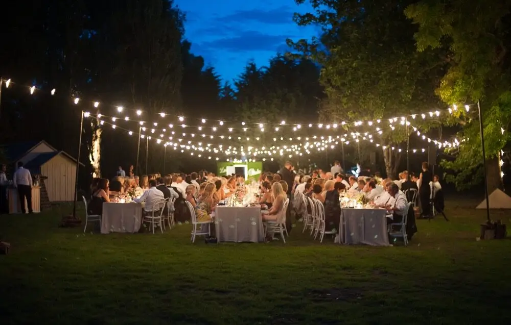 Outdoor night reception decorated with overhead hanging festoon light canopy