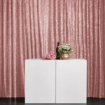 Blush pink pleated drape backdrop with white display table setup.