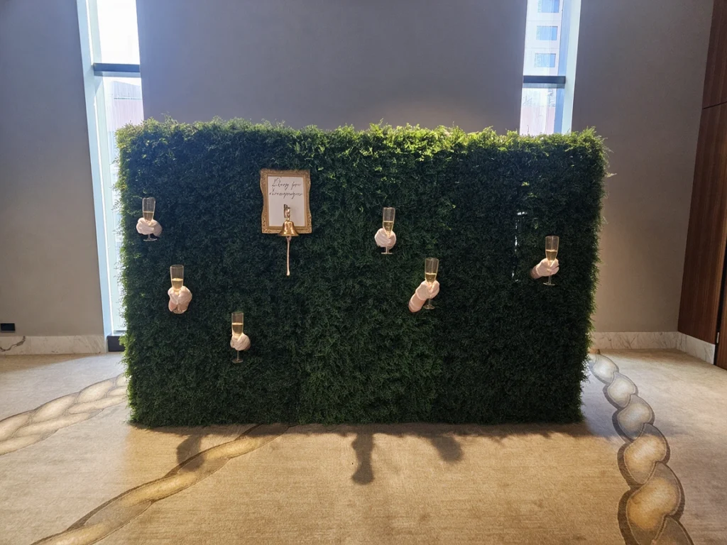 Lush green hedge backdrop set up inside event space
