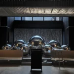 Indoor venue with reflective silver sphere decor lining floor near gray drapes.