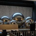 Event room decorated with silver orbs arranged in front of gray sheer backdrop.