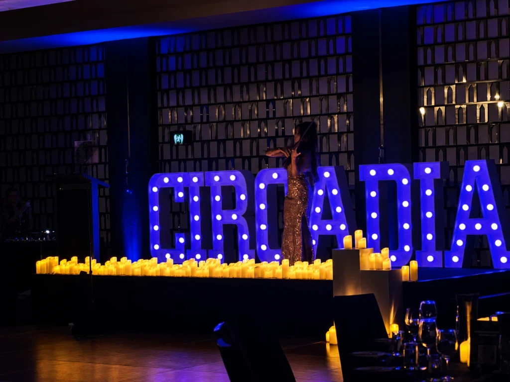 Illuminated marquee letters spelling "CIRCADIAN" in dark event space.