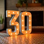 Illuminated marquee number 30 with surrounding balloon party decor