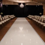 Glossy white wedding aisle runner surrounded by guest seating
